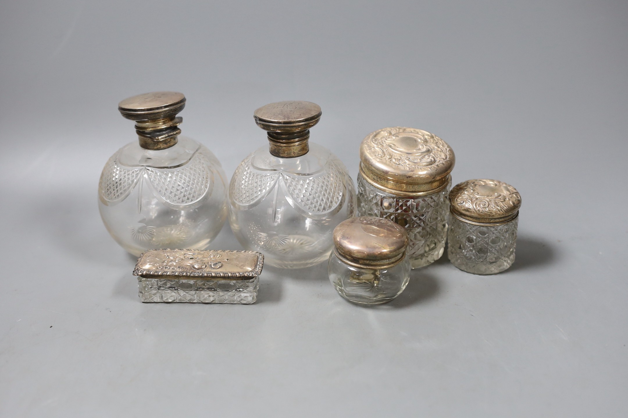 A pair of George V silver topped cut glass scent bottles, 11cm and four silver topped toilet jars.